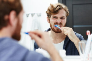 man brushing teeth in mirror