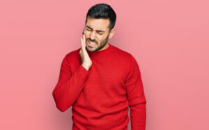 man in red t-shirt with tooth ache pain