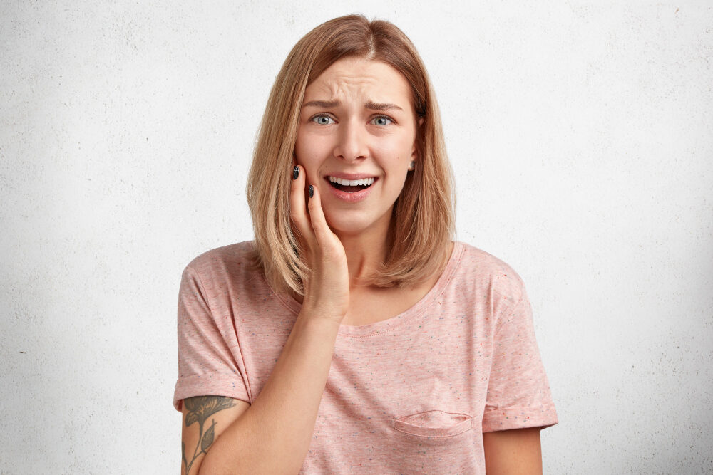 woman with cracked tooth pain hand holding face