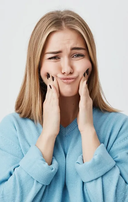 young woman with TMJ jaw pain holding both sides of face