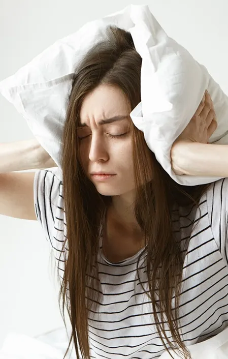 woman holding pillow over her head cannot sleep