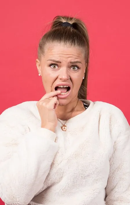 woman white jumper holding teeth might have gingivitis