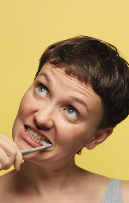 woman with short hair brushing teeth