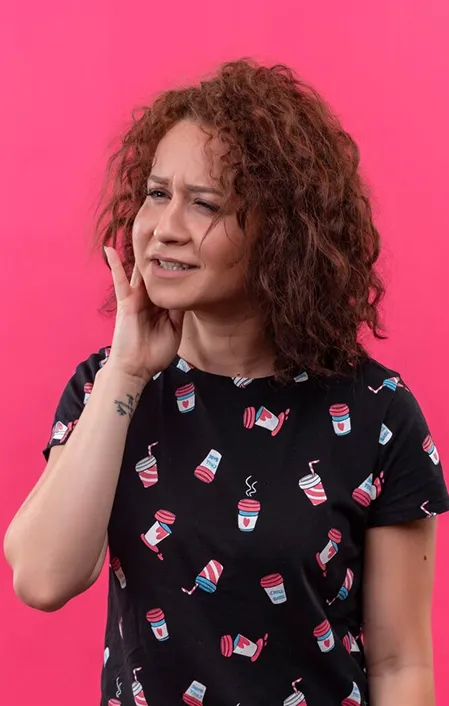 woman with curly hair holding side of face with a cracked tooth