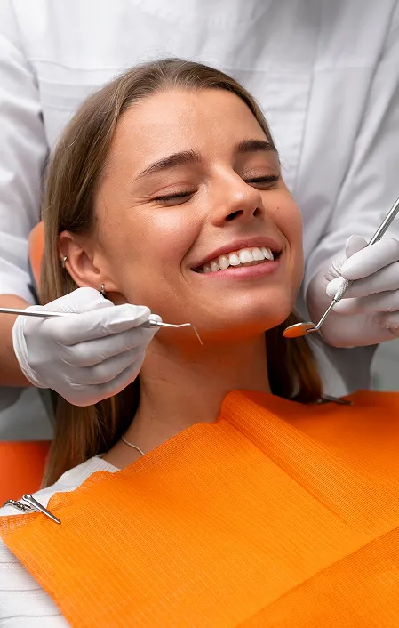 woman in dental chair with orange bib smiling at the end of tooth filling appointment