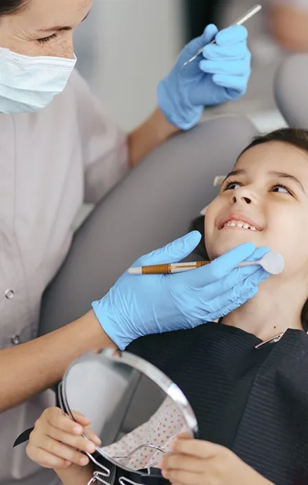 young child sitting in dental chair smiling at dentist